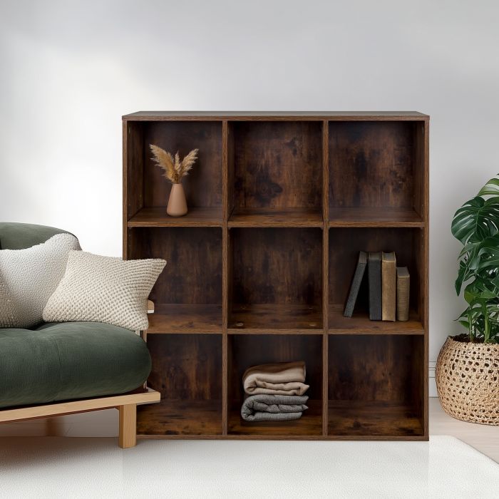 A dark brown room divider with decorative items stands next to a green sofa in front of a white wall.